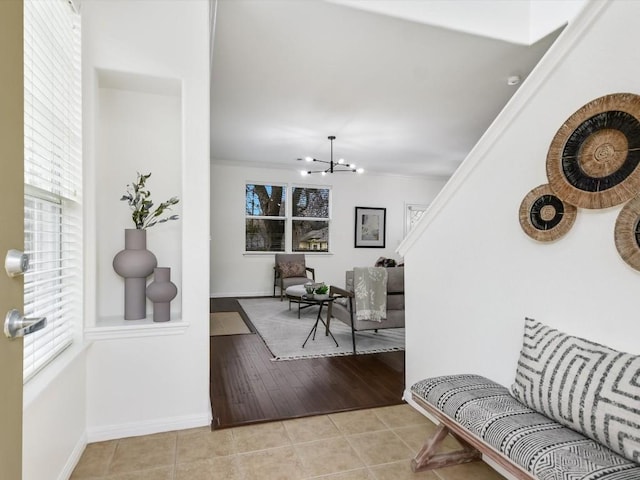 tiled foyer featuring an inviting chandelier and ornamental molding