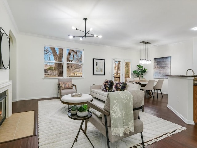 living room with hardwood / wood-style floors, crown molding, a fireplace, and a chandelier