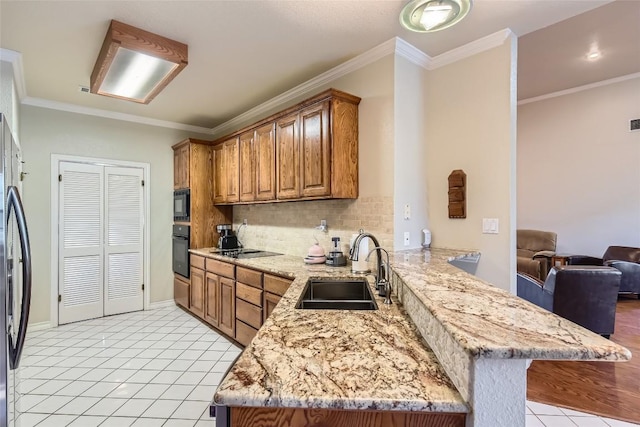 kitchen with kitchen peninsula, a breakfast bar, sink, black appliances, and light tile patterned flooring