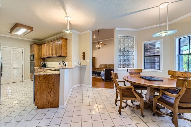 kitchen featuring sink, kitchen peninsula, pendant lighting, light tile patterned flooring, and black appliances