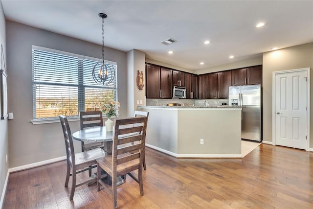 kitchen with pendant lighting, dark brown cabinets, stainless steel appliances, and tasteful backsplash