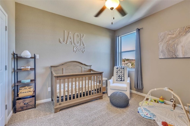 carpeted bedroom with ceiling fan and a nursery area