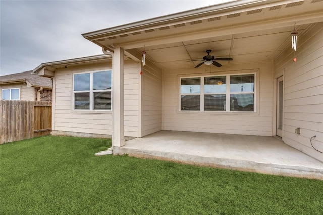 view of exterior entry featuring ceiling fan, a yard, and a patio