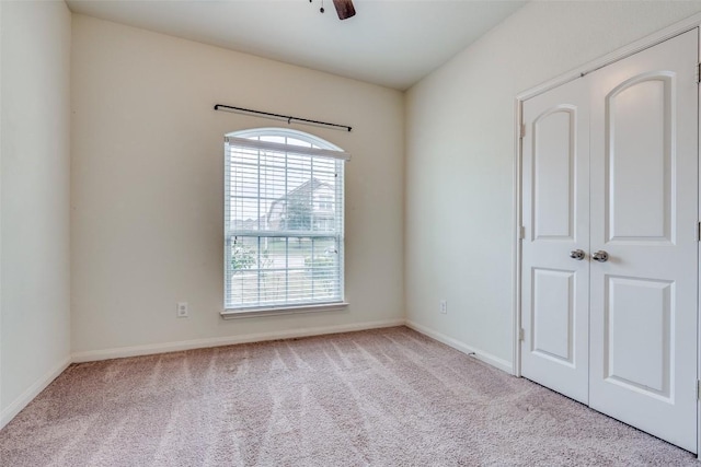 spare room with ceiling fan and light colored carpet