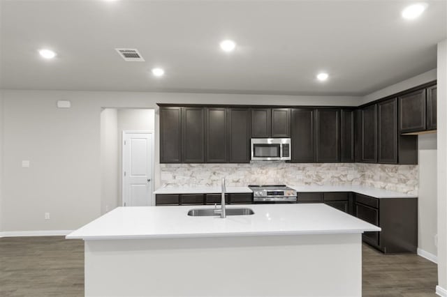 kitchen featuring appliances with stainless steel finishes, sink, a center island with sink, and backsplash