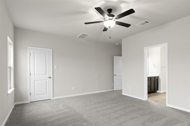 unfurnished bedroom featuring connected bathroom, light colored carpet, and ceiling fan