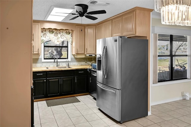 kitchen with ceiling fan with notable chandelier, sink, a skylight, light tile patterned floors, and appliances with stainless steel finishes