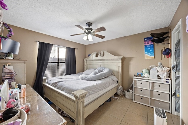 bedroom featuring ceiling fan, light tile patterned floors, and a textured ceiling