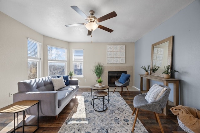 living room with ceiling fan, dark hardwood / wood-style flooring, and a tiled fireplace