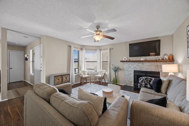 living room featuring a textured ceiling, a fireplace, ceiling fan, and dark wood-type flooring