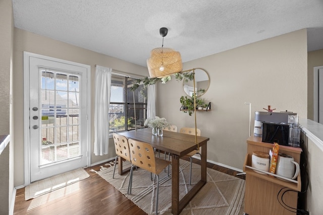 dining area featuring dark wood-type flooring and a textured ceiling