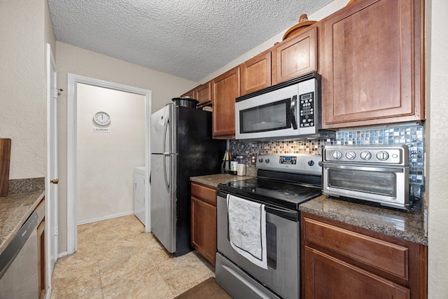 kitchen featuring decorative backsplash, washer / dryer, a textured ceiling, and stainless steel appliances