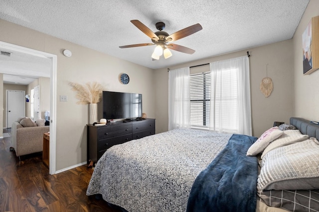 bedroom with ceiling fan, dark wood-type flooring, and a textured ceiling