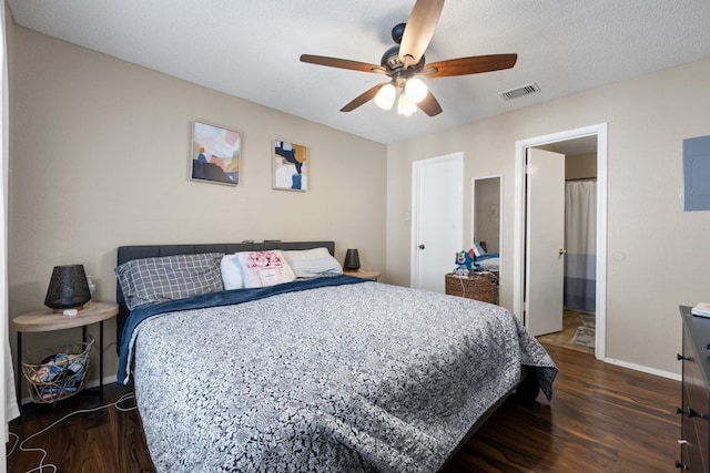 bedroom with a textured ceiling, dark hardwood / wood-style flooring, electric panel, and ceiling fan