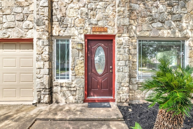 doorway to property featuring an attached garage and stone siding