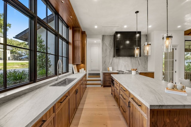 bar with sink, hanging light fixtures, light hardwood / wood-style flooring, decorative backsplash, and light stone countertops