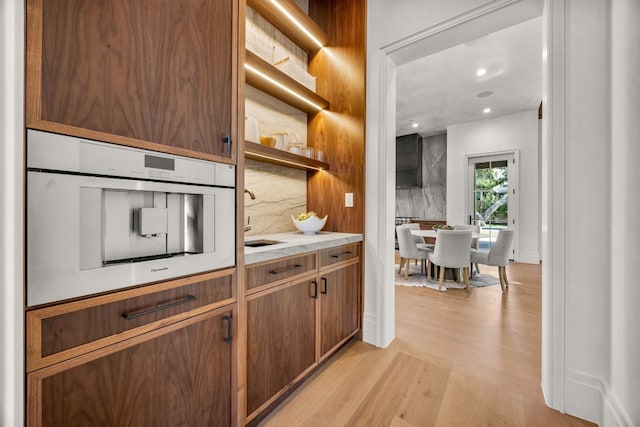 kitchen with backsplash, light hardwood / wood-style flooring, oven, and sink