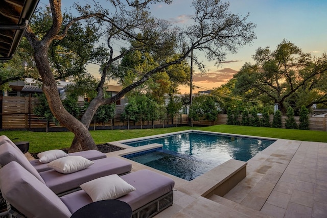 pool at dusk with an in ground hot tub, a patio area, and a lawn