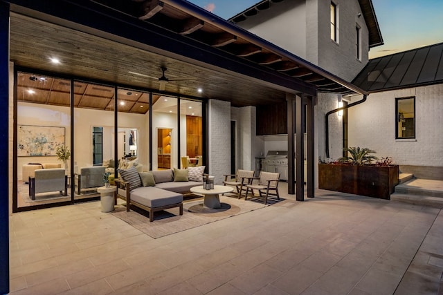 patio terrace at dusk featuring outdoor lounge area, an outdoor kitchen, and area for grilling