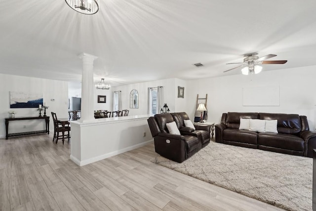 living room with ceiling fan with notable chandelier, light wood-type flooring, and decorative columns