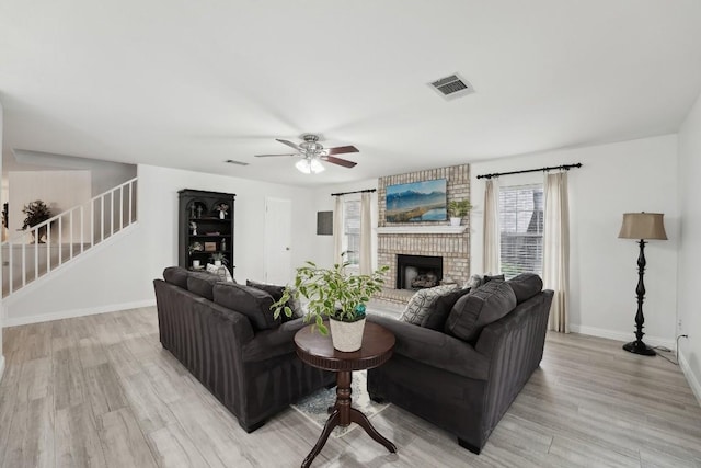 living room featuring ceiling fan, a fireplace, and light hardwood / wood-style floors