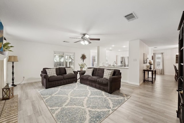 living room with ceiling fan, light wood-type flooring, and sink