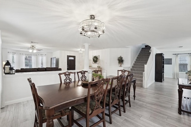 dining area featuring ceiling fan with notable chandelier, light hardwood / wood-style floors, and ornate columns