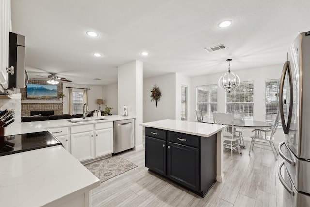 kitchen featuring stainless steel appliances, sink, a center island, white cabinetry, and hanging light fixtures