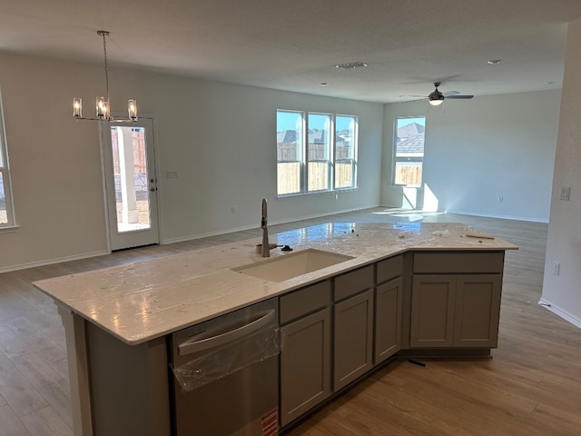 kitchen with light wood finished floors, open floor plan, a sink, gray cabinetry, and stainless steel dishwasher