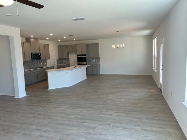 kitchen with appliances with stainless steel finishes, backsplash, and gray cabinetry