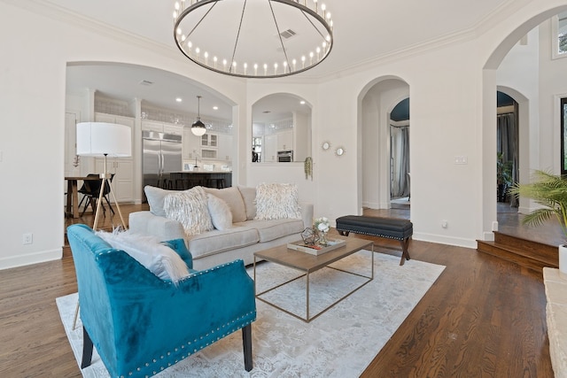 living room featuring wood-type flooring, ornamental molding, and a notable chandelier