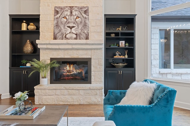 living room with a stone fireplace, wood-type flooring, and a wealth of natural light