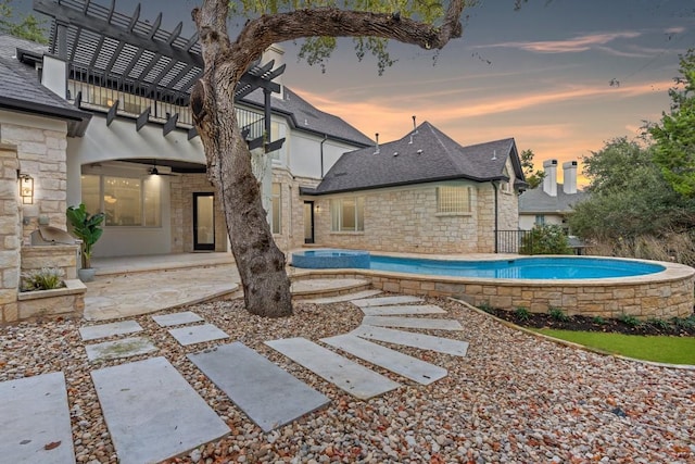 pool at dusk with a jacuzzi, a pergola, ceiling fan, and a patio area