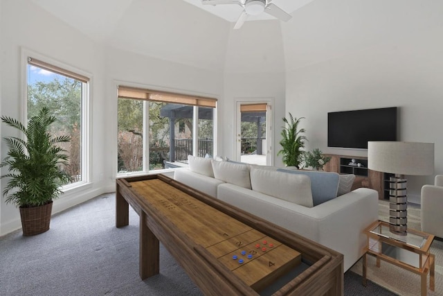 living room featuring ceiling fan, carpet floors, and a towering ceiling