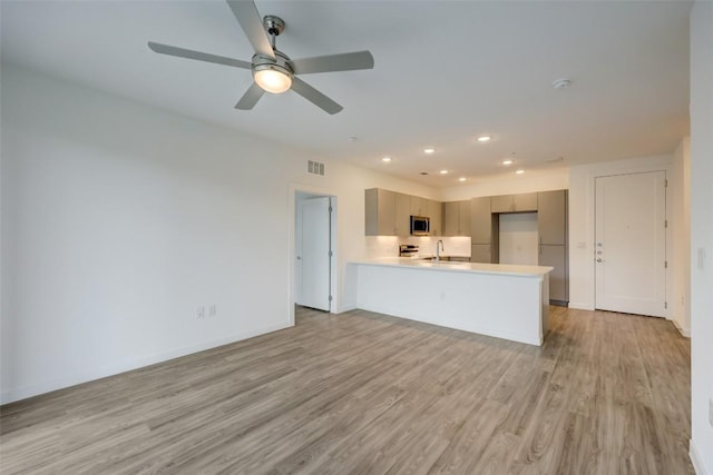 kitchen featuring kitchen peninsula, light hardwood / wood-style floors, ceiling fan, and sink