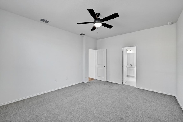 unfurnished bedroom featuring ensuite bath, carpet flooring, baseboards, and visible vents