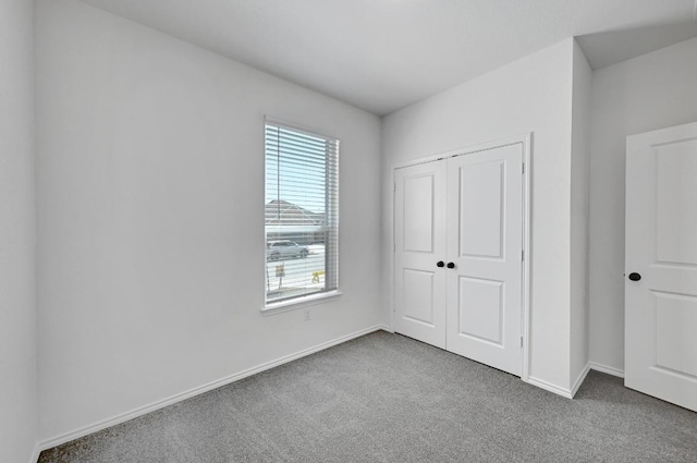 unfurnished bedroom with a closet, baseboards, and carpet