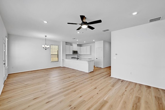 unfurnished living room featuring recessed lighting, visible vents, light wood-style flooring, and ceiling fan with notable chandelier