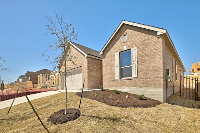 view of property exterior with a garage, brick siding, driveway, and fence