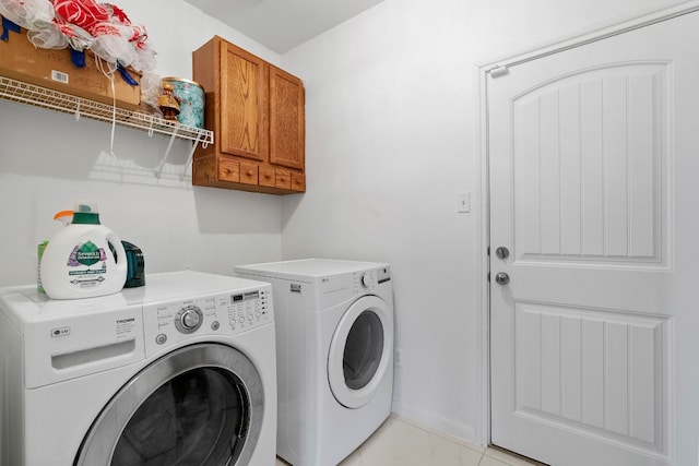 washroom featuring separate washer and dryer, light tile patterned floors, and cabinets