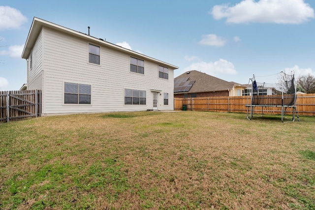 back of house featuring a yard and a trampoline