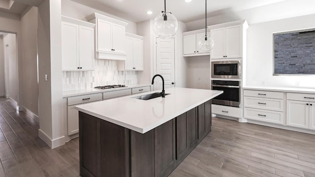 kitchen with light countertops, appliances with stainless steel finishes, a sink, and tasteful backsplash