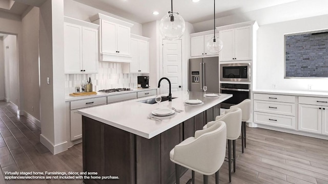 kitchen featuring tasteful backsplash, a kitchen bar, light countertops, stainless steel appliances, and a sink