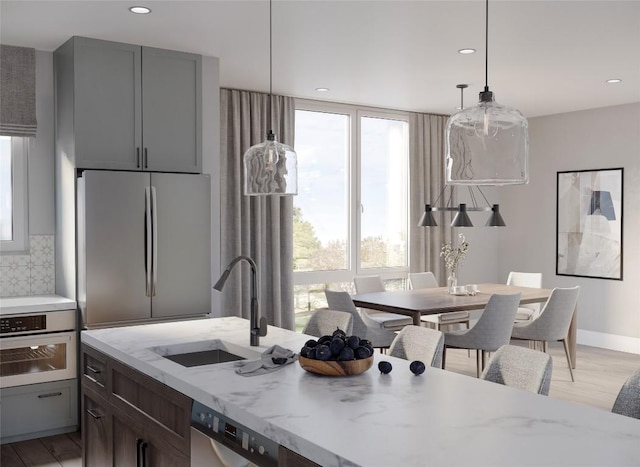 kitchen with gray cabinetry, sink, light hardwood / wood-style flooring, decorative backsplash, and appliances with stainless steel finishes