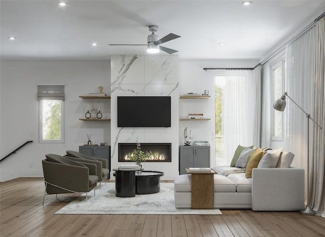 living room with ceiling fan, a fireplace, and light hardwood / wood-style floors