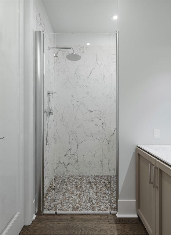 bathroom featuring a tile shower, hardwood / wood-style floors, and vanity