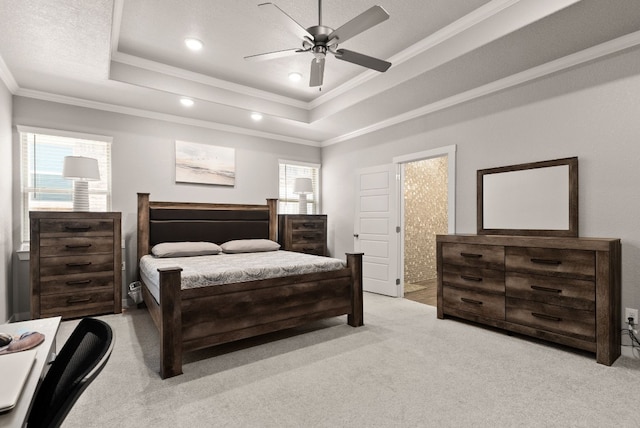 bedroom featuring ceiling fan, light colored carpet, crown molding, and a tray ceiling