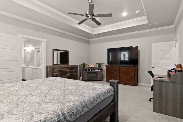 bedroom featuring ensuite bath, light colored carpet, a tray ceiling, ceiling fan, and crown molding