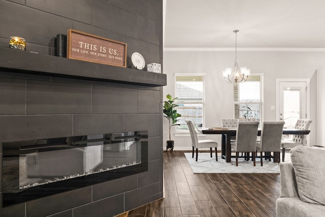 kitchen with a tiled fireplace, crown molding, decorative light fixtures, and a notable chandelier