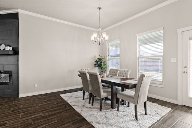 dining area with a tiled fireplace, a notable chandelier, and ornamental molding